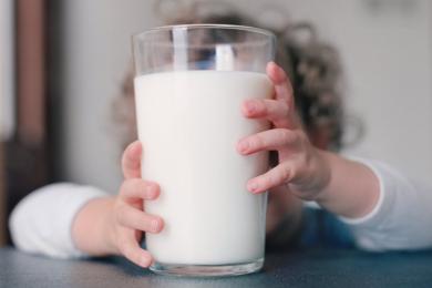 ребенок держит стакан молока