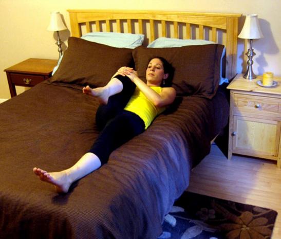 женщина делает упражнения на кровати