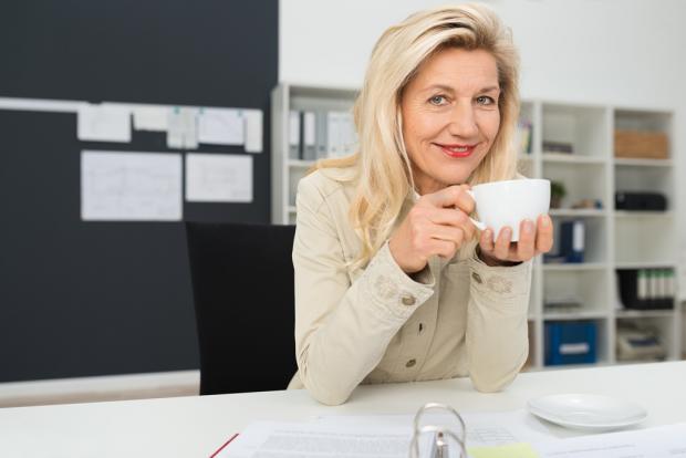 зрелая женщина пьет чай на работе