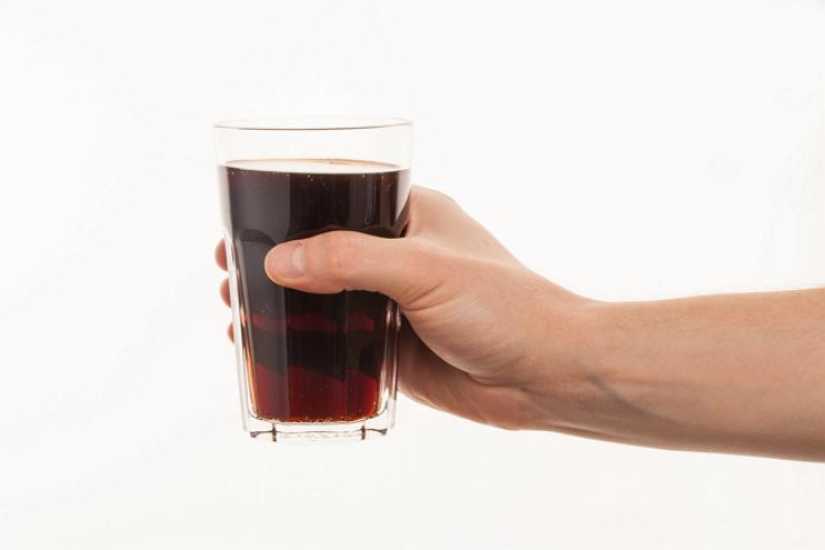 Hand holding fresh cold glass of dark beer or kvass