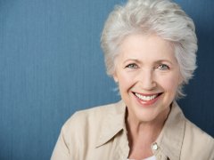 : Beautiful elegant elderly lady with a lively smile looking directly at the camera while posing against a green background with copyspace
