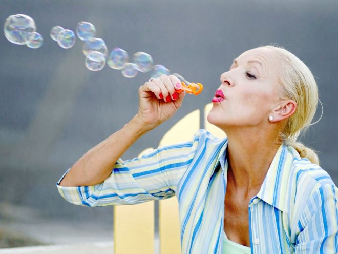 зрелая женщина дует пузыри