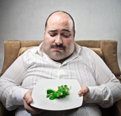 торлстый мужчина держит тарелку с салатом в руках