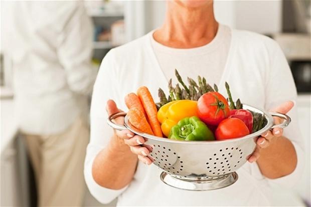 женщина держит в руках вазу с овощами