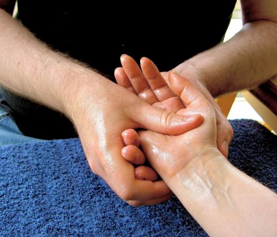 мужчина делает массаж рук женщине