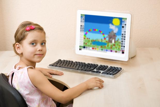 Маленькая девочка рисует на компьютере