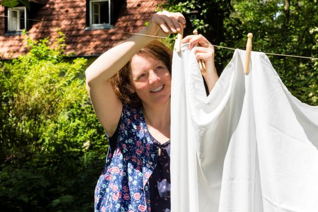 женщина развешивает постельное белье на веревке