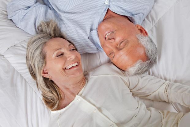 зрелая пара в постеле смеется