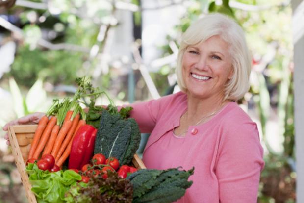 женщина держит в руках ящик с овощами