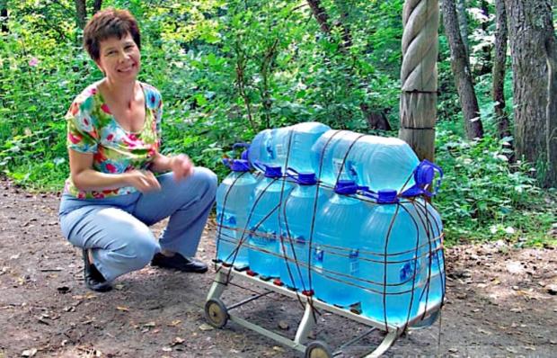 женщина перевозит бутылки с водой на тачке