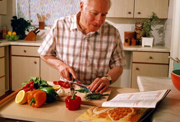 зрелый мужчина готовит еду