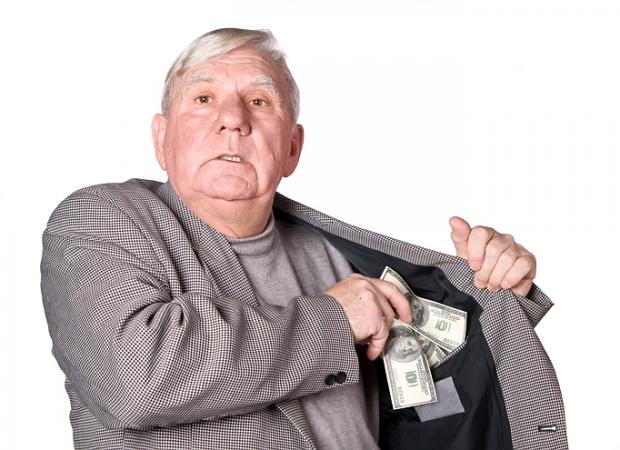 Elderly man puts money in an internal pocket of a jacket. It is isolated on a white background