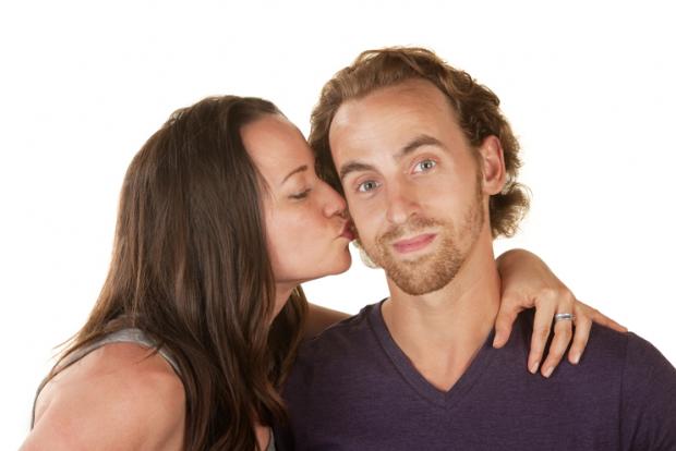 Calm bearded man kissed by woman over isolated background