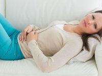 stories.mywiserhealth.com: женщина лежит на диване и держится руками за живот