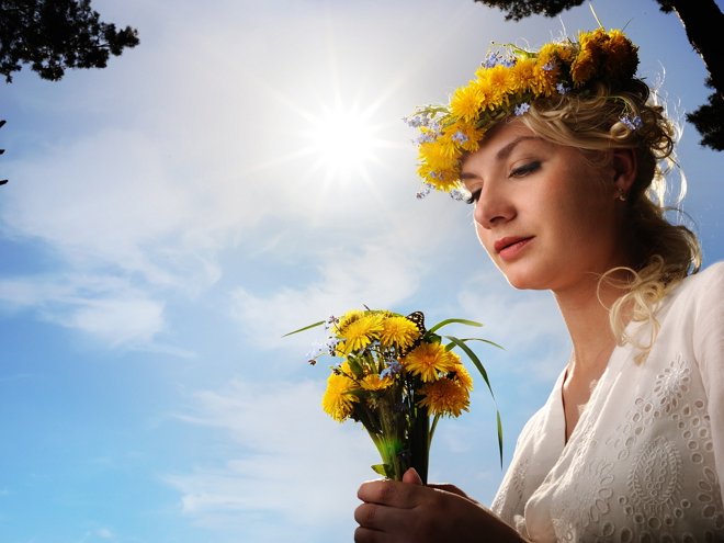 Beautiful woman with dandelion flowers over blue sky