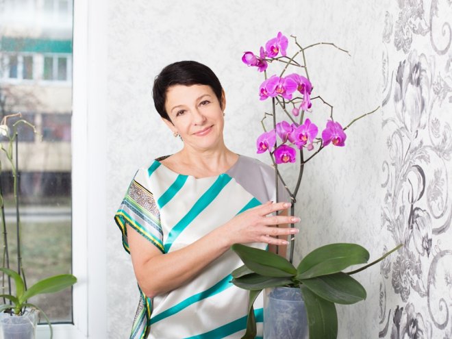 зрелая женщина держит в руках орхидею