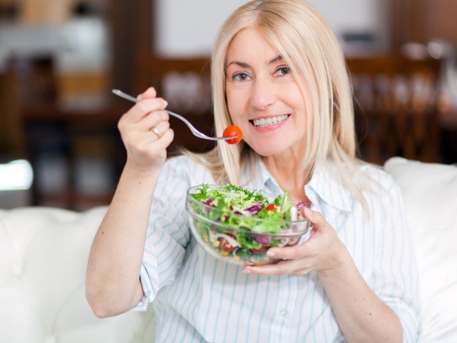 зрелая женщина ест салат